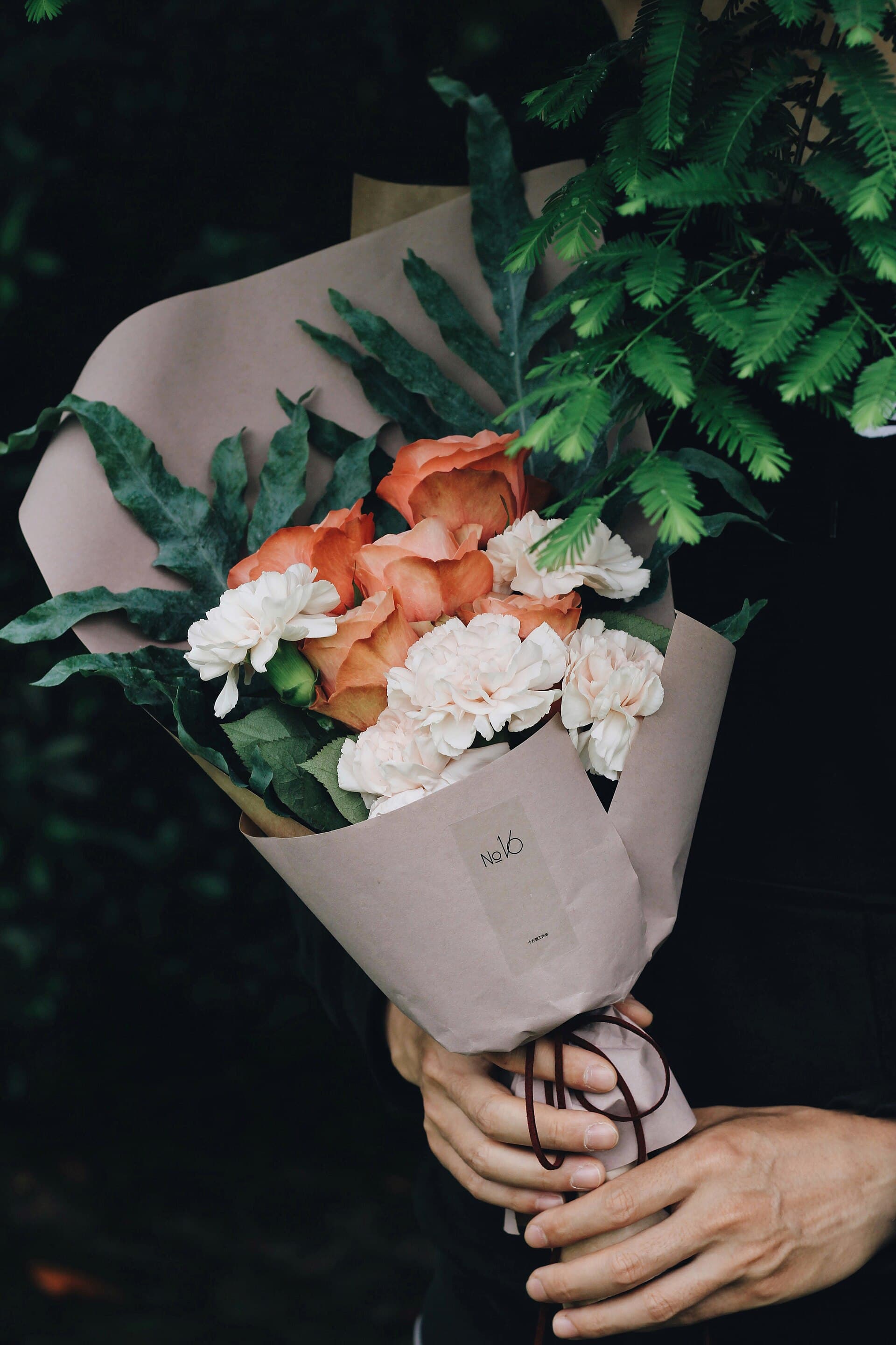 A paper-wrapped bouquet of roses and carnations
